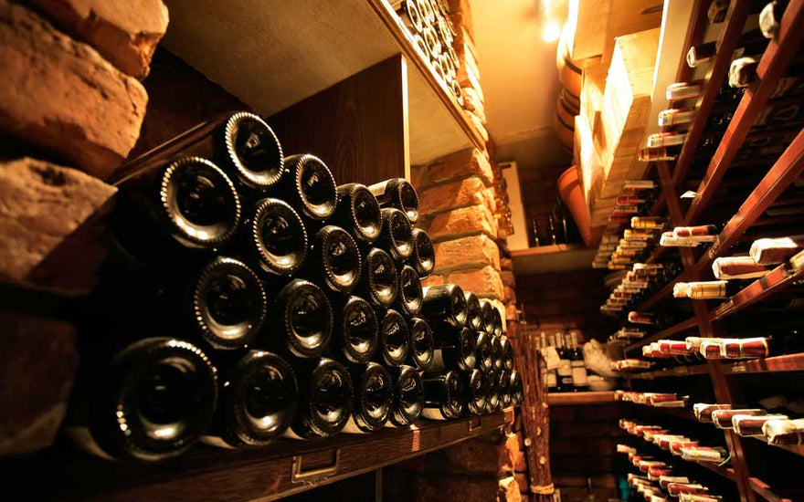 Cabecera con botellas de vino en una bodega